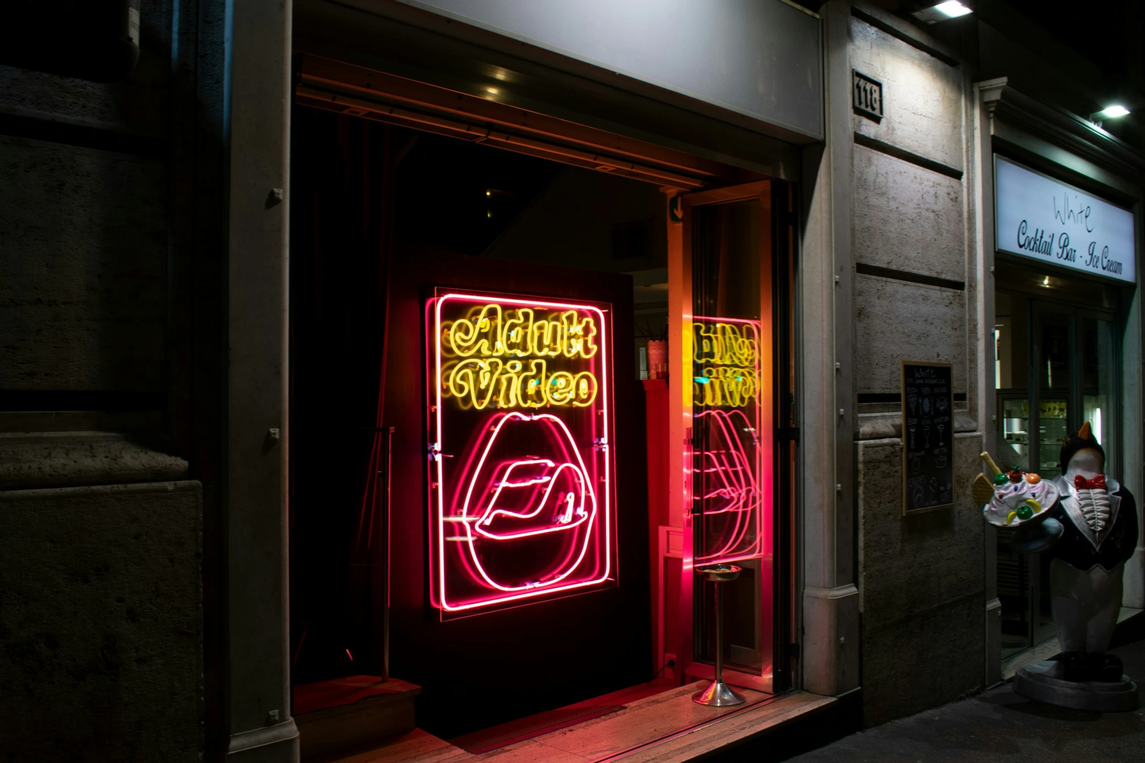 two people in a doorway with a neon sign on the side