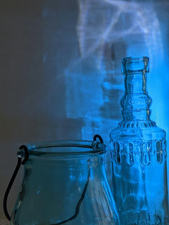 two glass bottles with handles and lids sitting next to each other