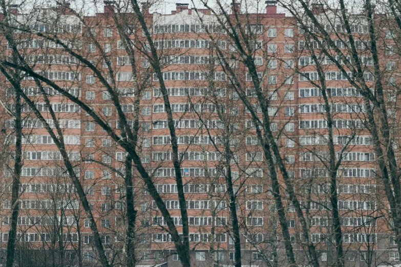 a tall red brick building next to trees in front of a parking lot