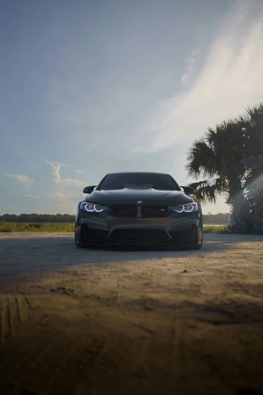 the front end of a silver car parked on a dirt road