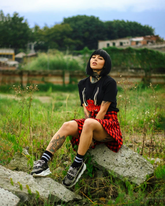 a woman wearing a red plaid skirt and black converses