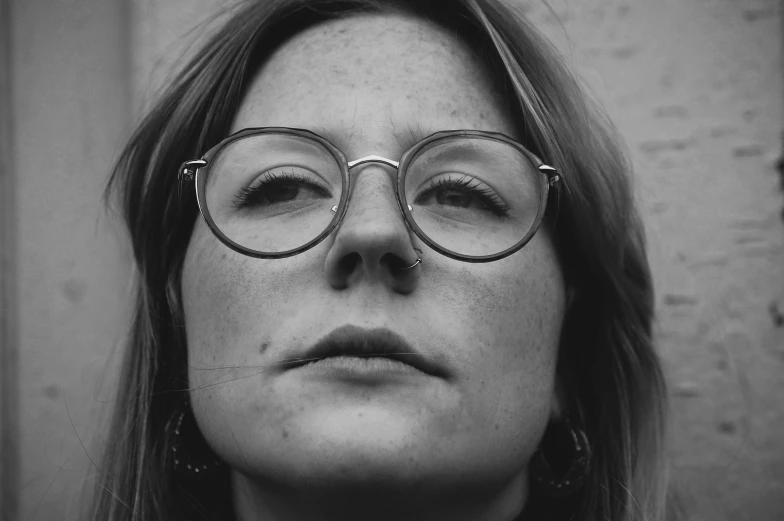 a black and white image of a woman wearing round glasses