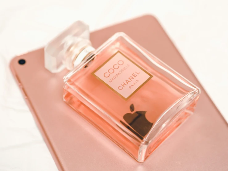 an apple a pink phone and a perfume bottle