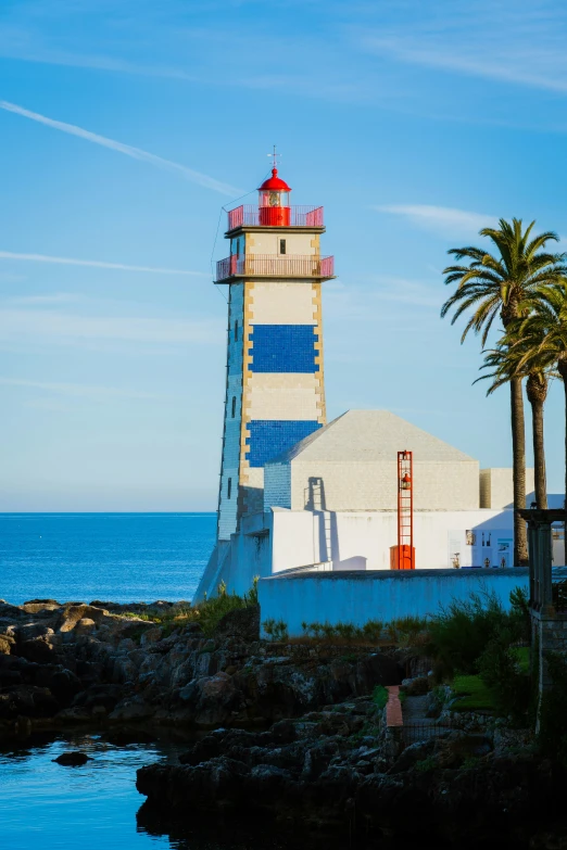 a lighthouse and palm trees by a body of water