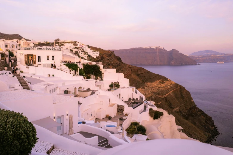 a white village is overlooking the water on a mountain