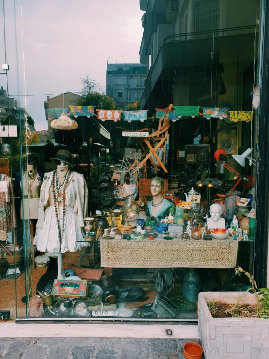 a storefront displays a table full of stuff and dolls