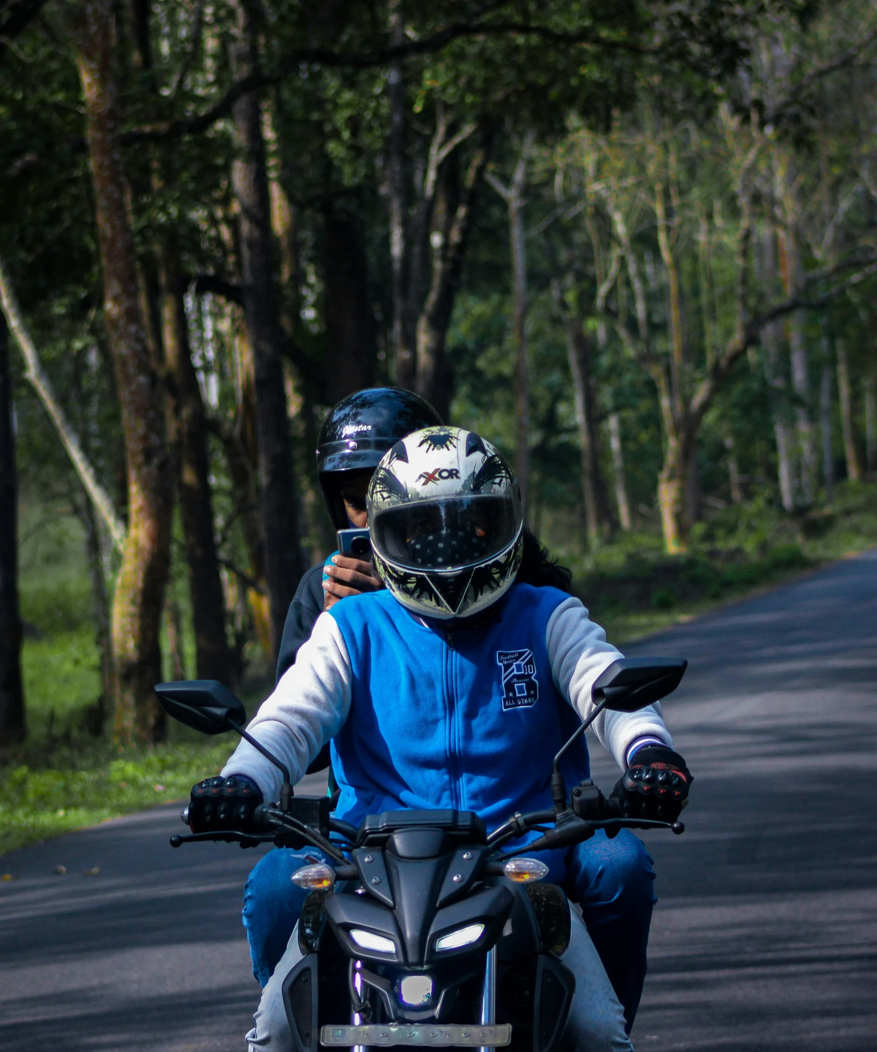 two people riding a motorcycle in the middle of a road