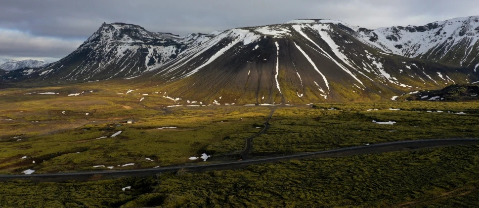 a group of mountains in the distance with road winding by