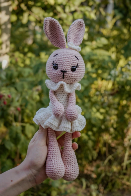 a crocheted bunny holding an apple in its hand