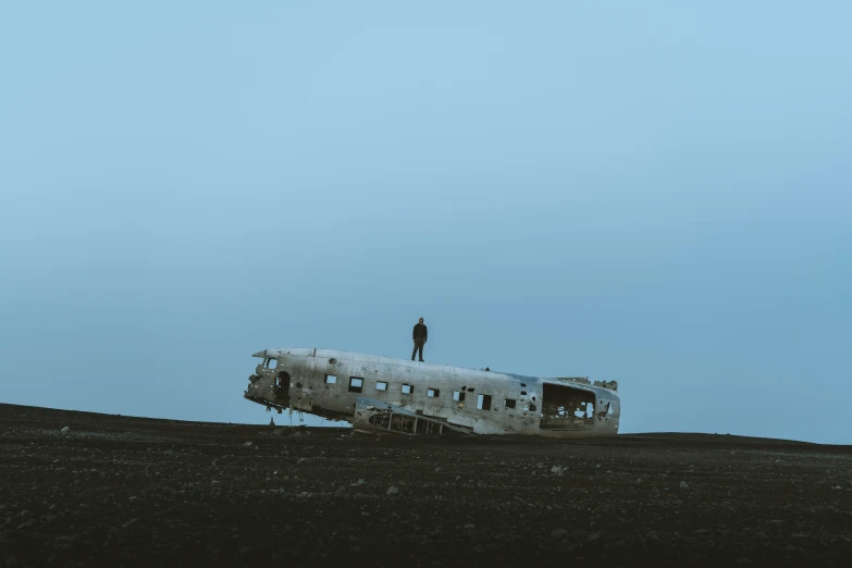 an airplane is sitting in a field, and one person is standing on top