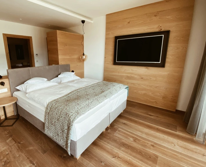 a bedroom with a bed and wooden wall and a tv on the wall