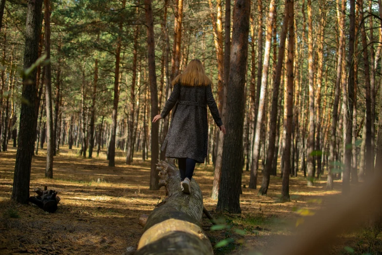 a girl in black dress walking in the woods