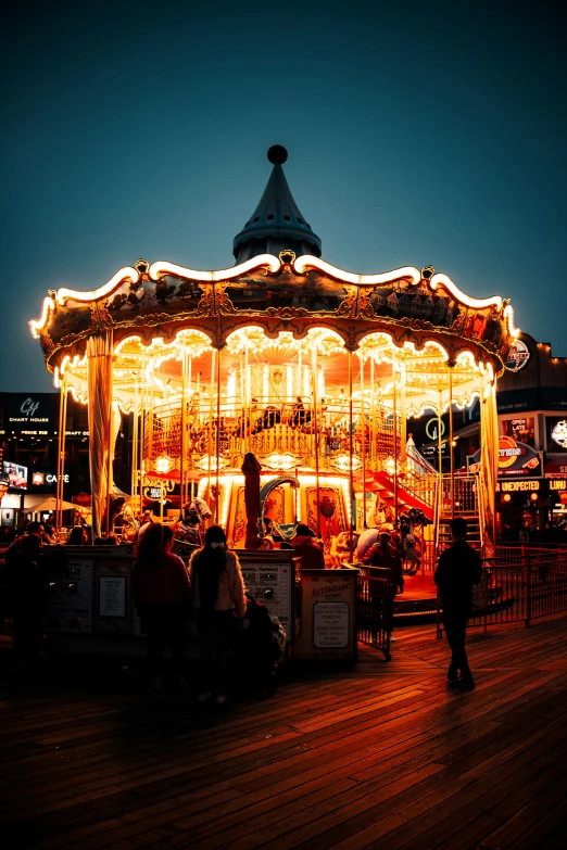 a carousel sits outside at night, with some lights on