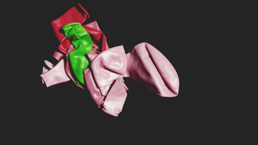 a pink bow with a green ribbon hanging on it