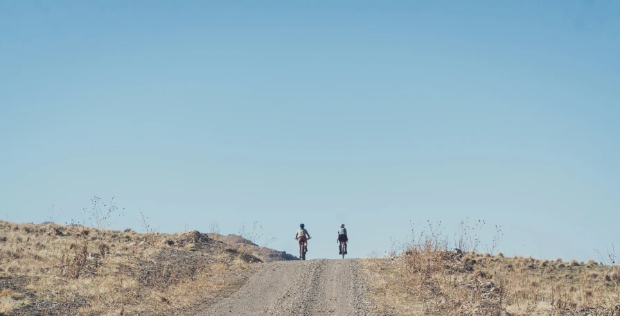 two people standing on top of a dirt hill