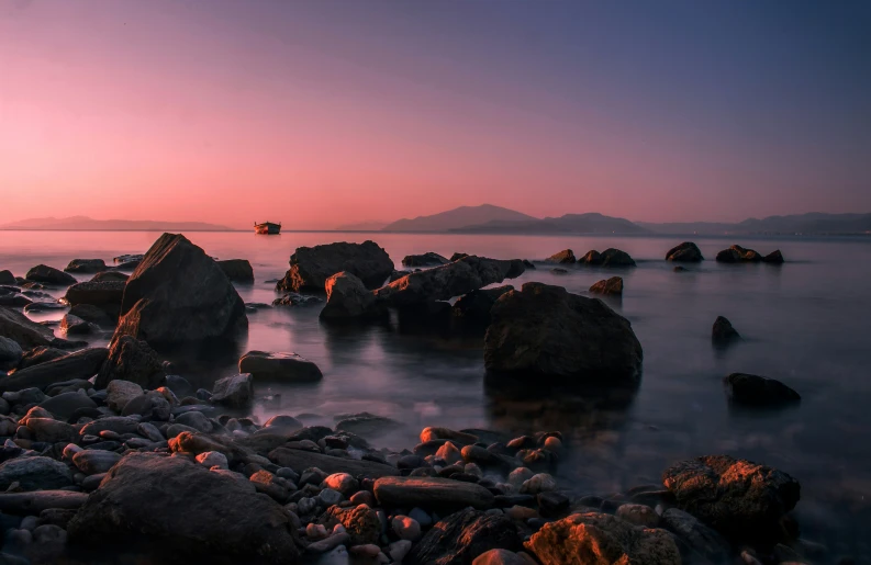 the water is dark with rocks and grass around