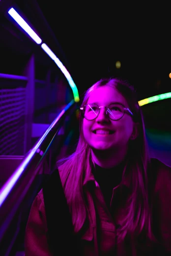 a smiling woman standing next to some neon lights