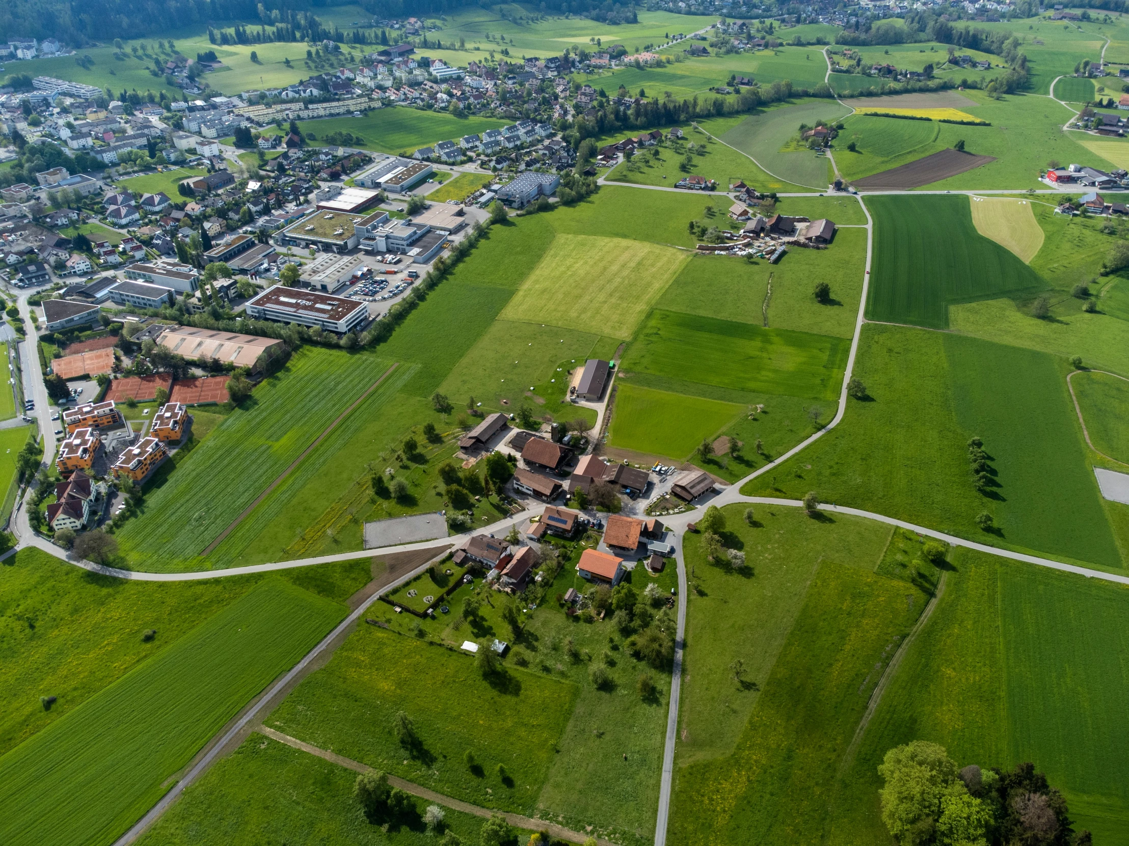 an aerial view of green land and large buildings