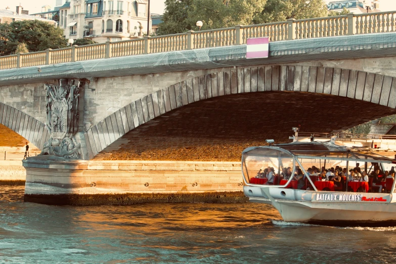 boat moving under a bridge while people look on