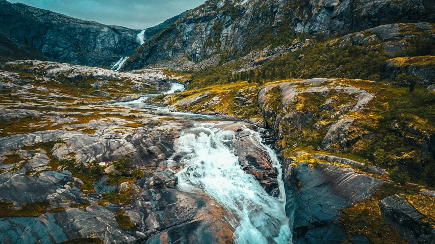 the waterfall that is running down to a cliff is surrounded by pine and moss