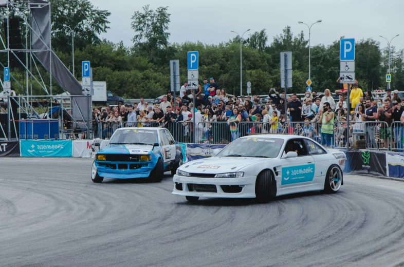 two cars racing on a race track with spectators