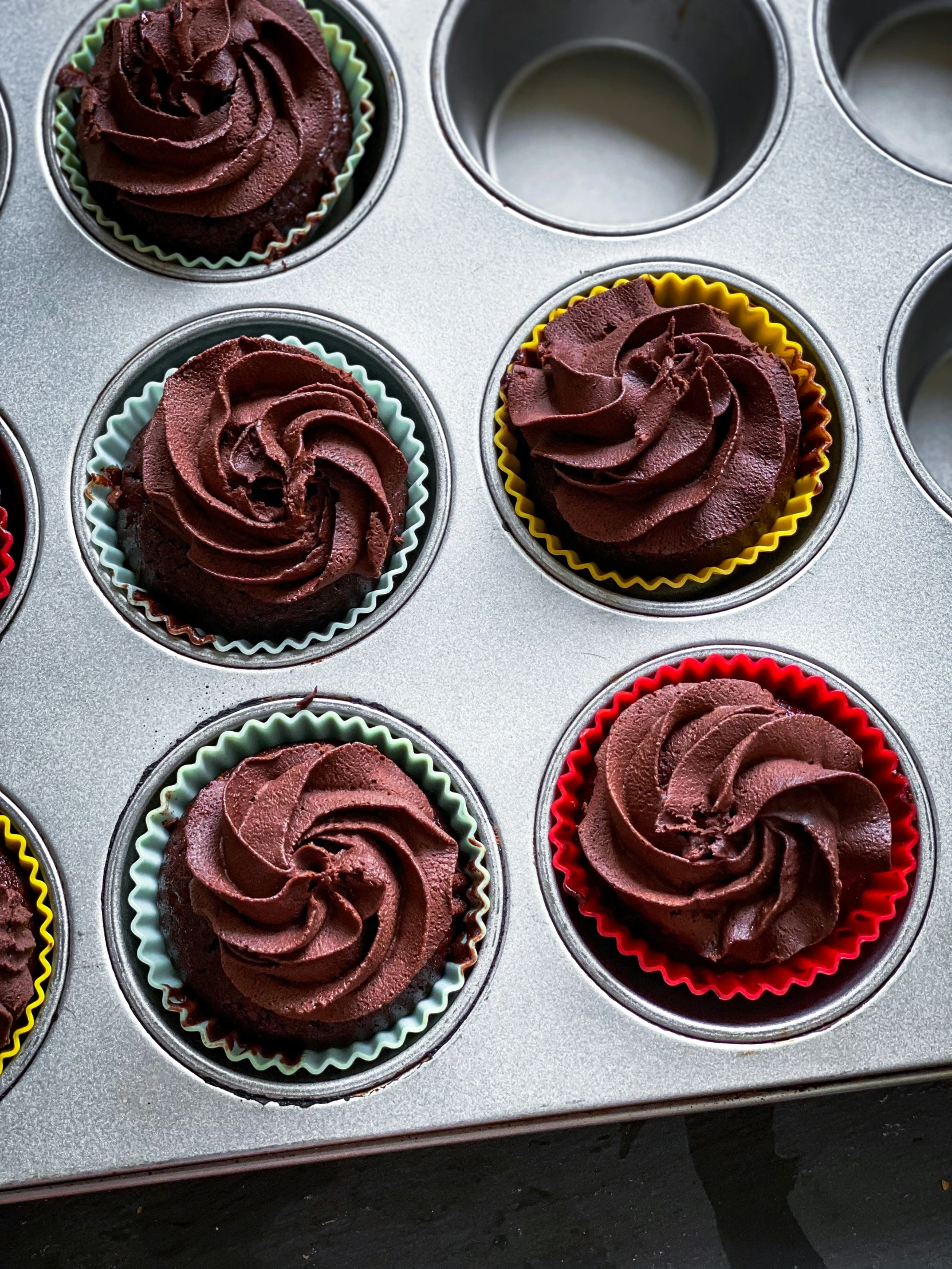 a muffin tin containing nine chocolate cupcakes