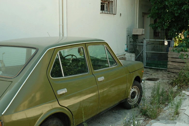 a green car parked on a narrow driveway