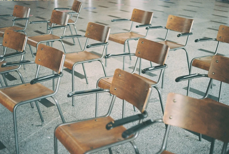 a row of wooden chairs sitting on a cement surface