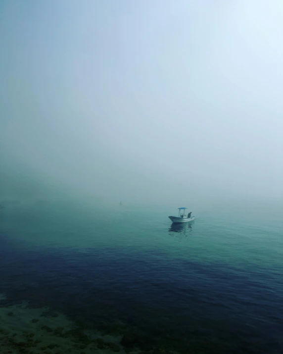 a small boat on a large body of water in the fog