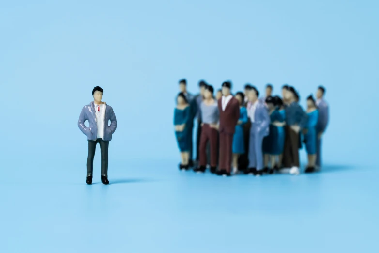 a group of tiny people stand behind a miniature model man