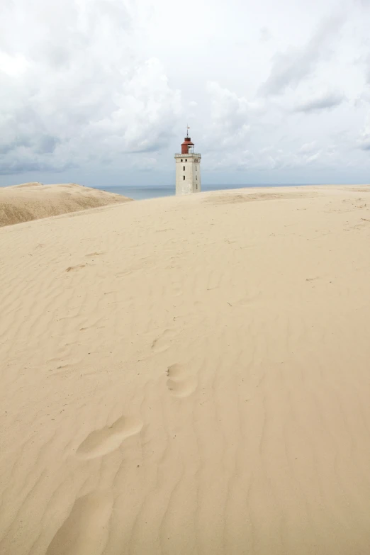 lighthouse in distance near cloudy sky on beach