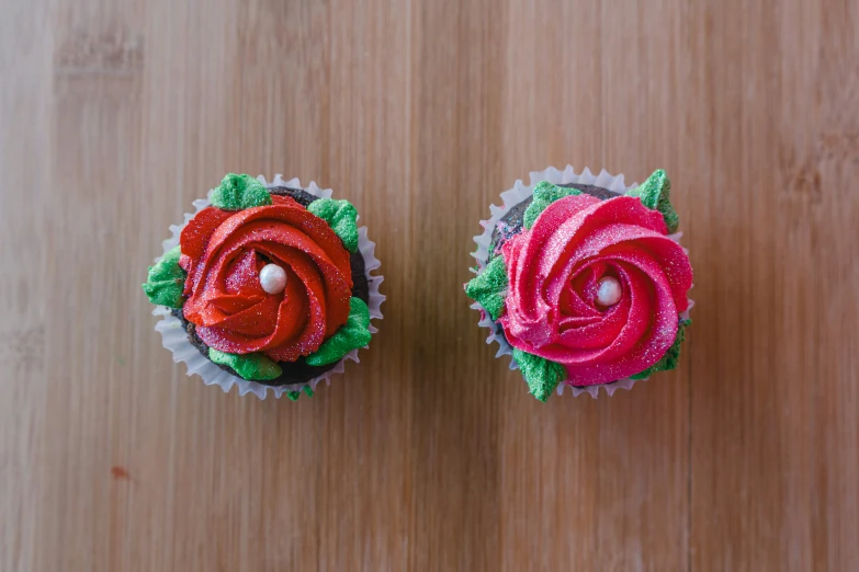 two cupcakes that are decorated in red, pink and green