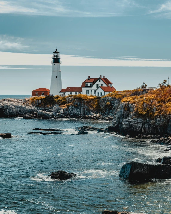 lighthouse at the end of cliff surrounded by water