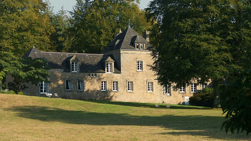 a large stone house sitting in a lush green field