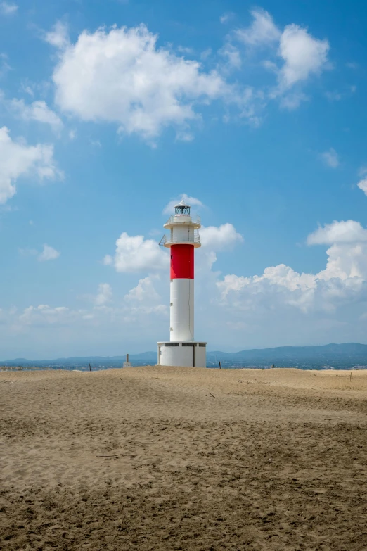 a white and red lighthouse is in the sand near the ocean