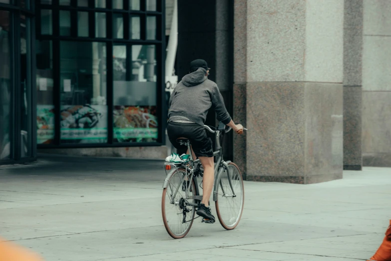 a man riding a bike down a sidewalk next to tall buildings