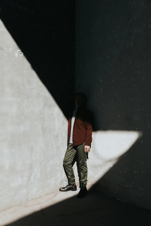 a boy standing near a wall with his feet up