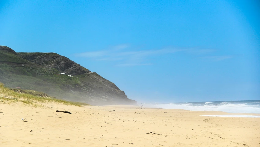 a beach with a big rock in the background