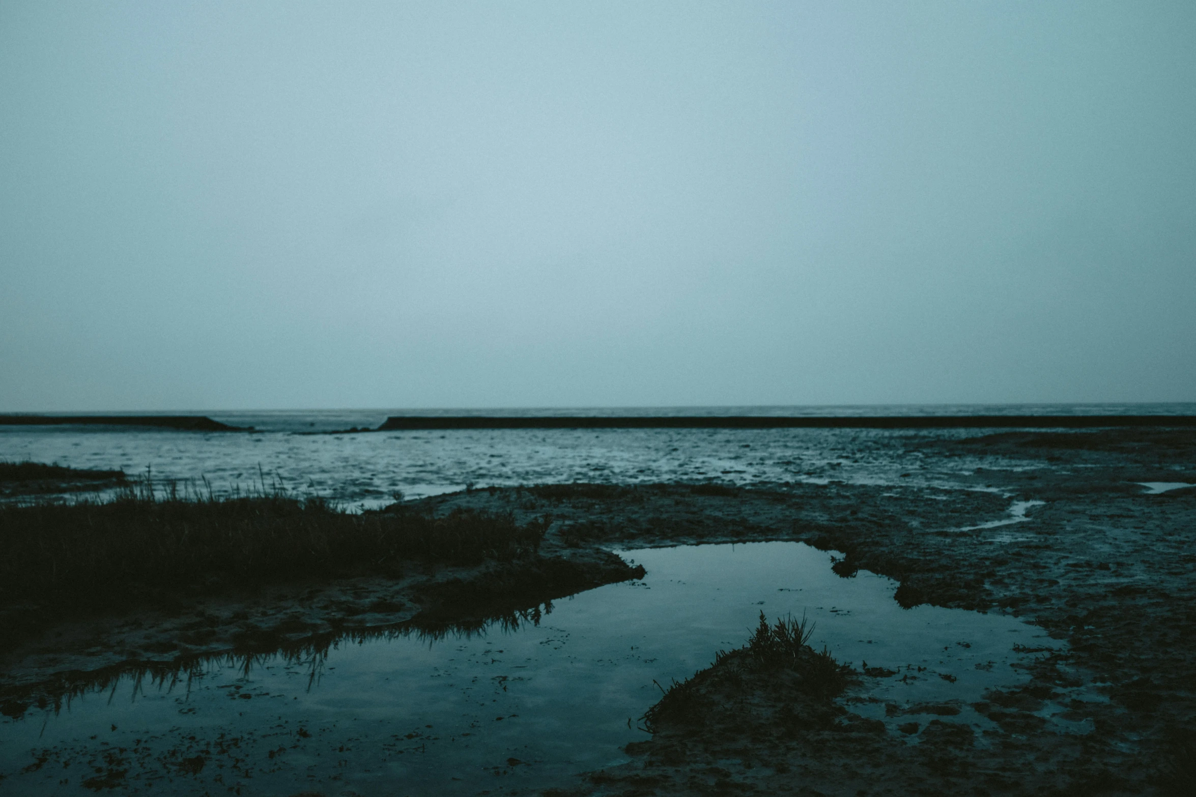 the view from an area along a bay with a dark water area