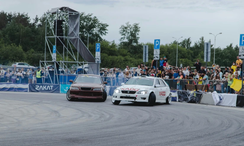 two cars in a race with people looking on