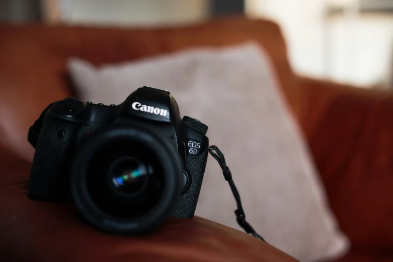 a canon camera sitting on top of a leather couch