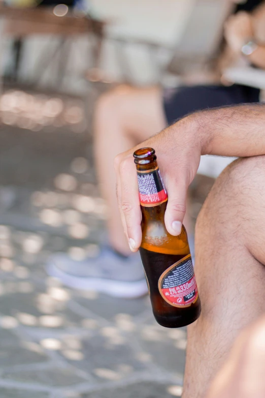 someone is holding a beer bottle and sitting