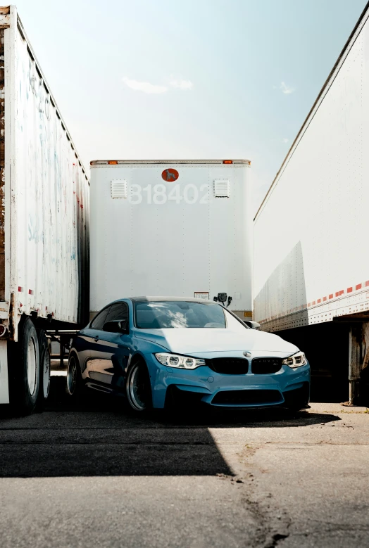 the blue and white car is parked next to the white semi truck