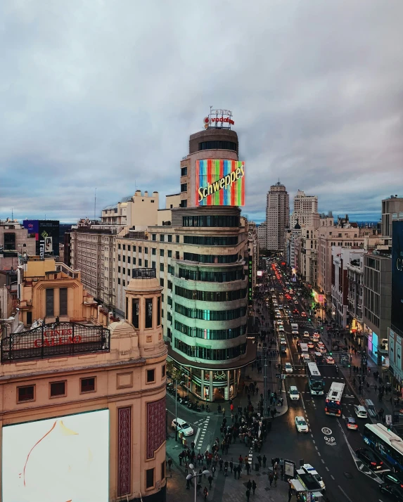 traffic in city street with multiple colored signs on large building