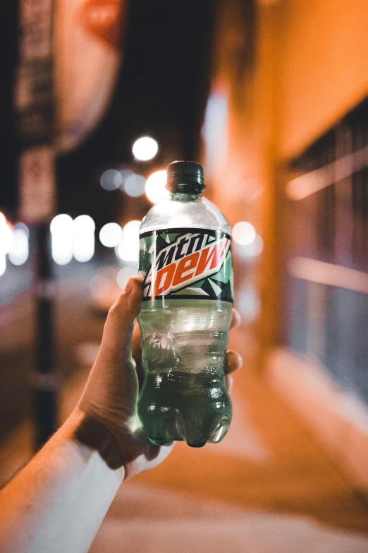 a person is handing out a soda bottle at night