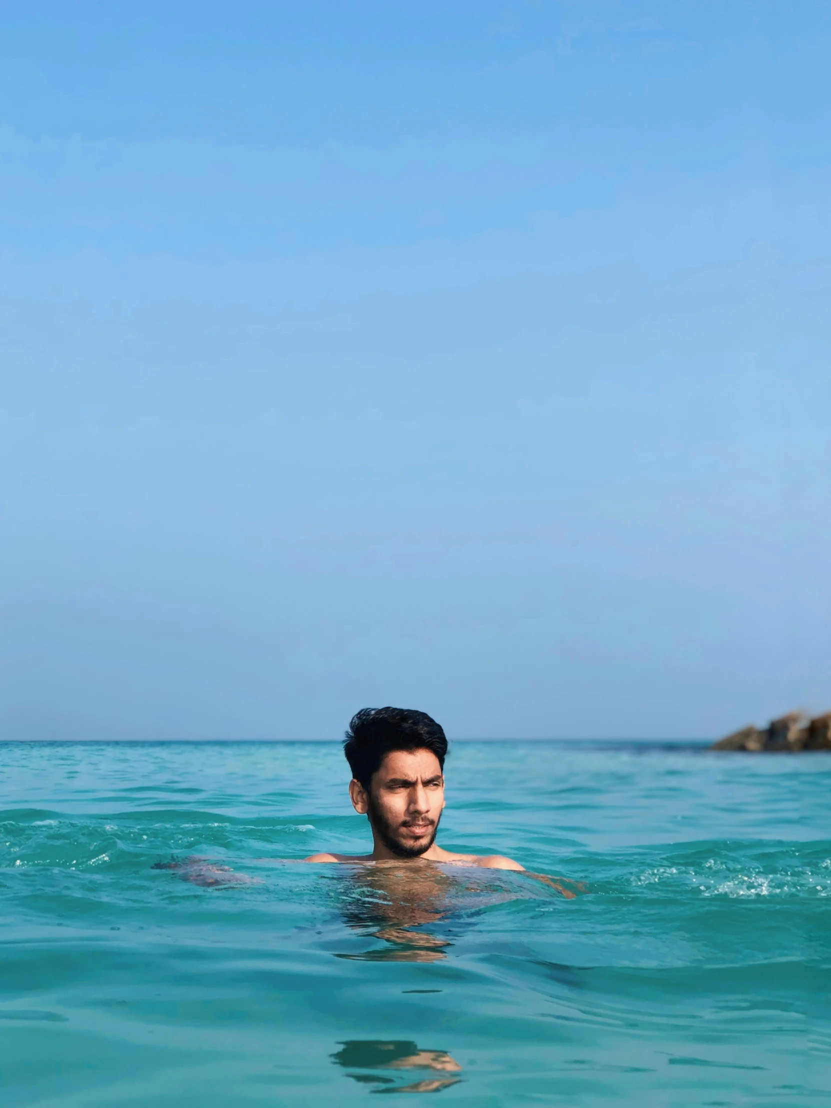 a man swims in the ocean, wearing his swimming trunks