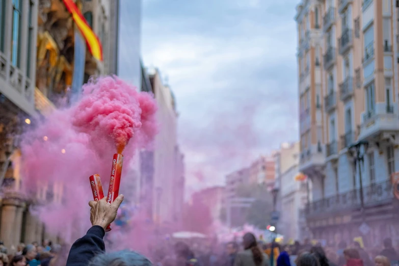 someone holds pink colored smoke in the air