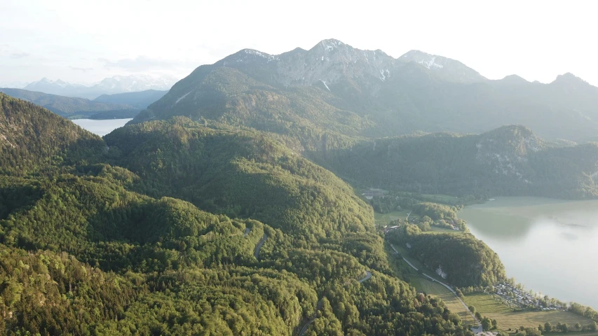 a green and lush forest covered hillside surrounded by mountains