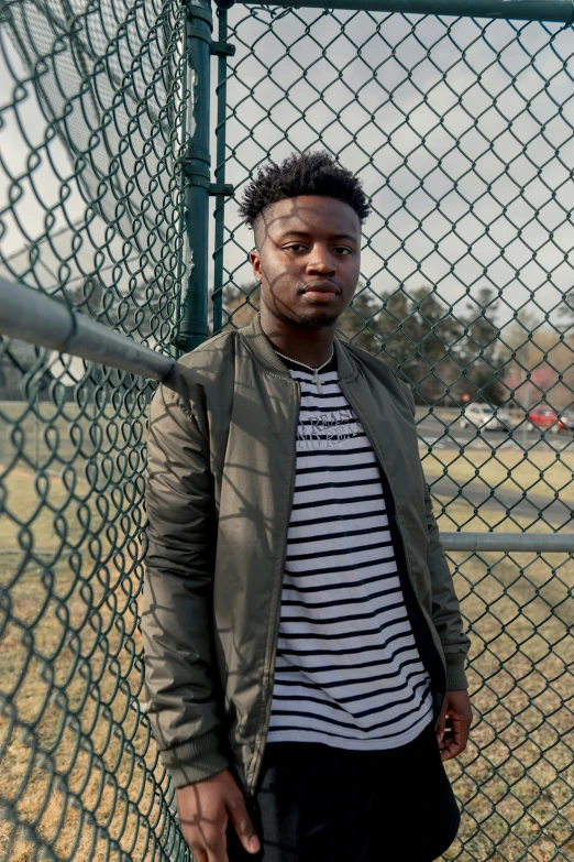 a man leaning against a chain link fence