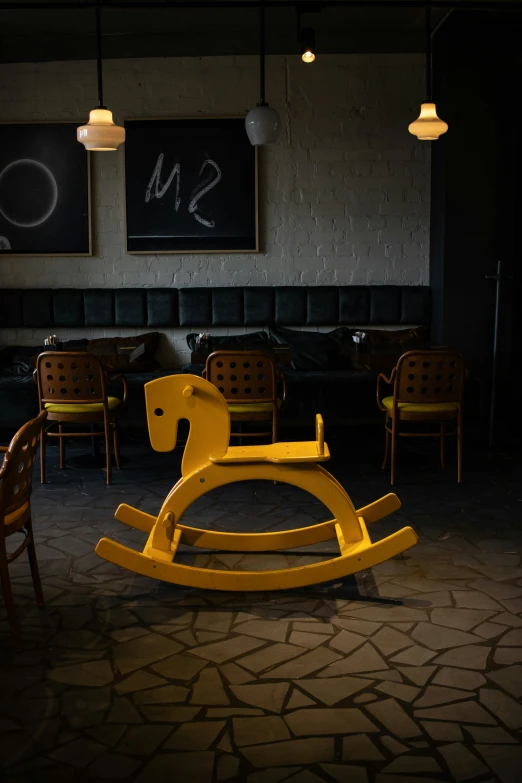 an empty room with yellow rocking horse in the foreground